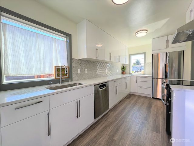 a kitchen with white cabinets and wooden floor