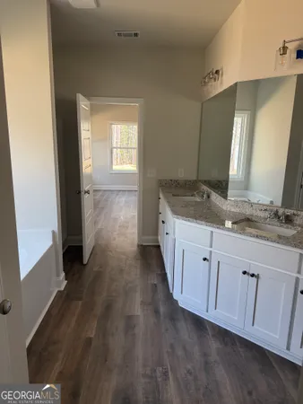a bathroom with a granite countertop double vanity sink and mirror