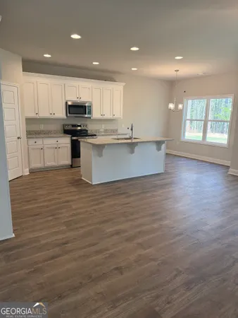 a large kitchen with stainless steel appliances granite countertop a large counter top a wooden floors and a fireplace