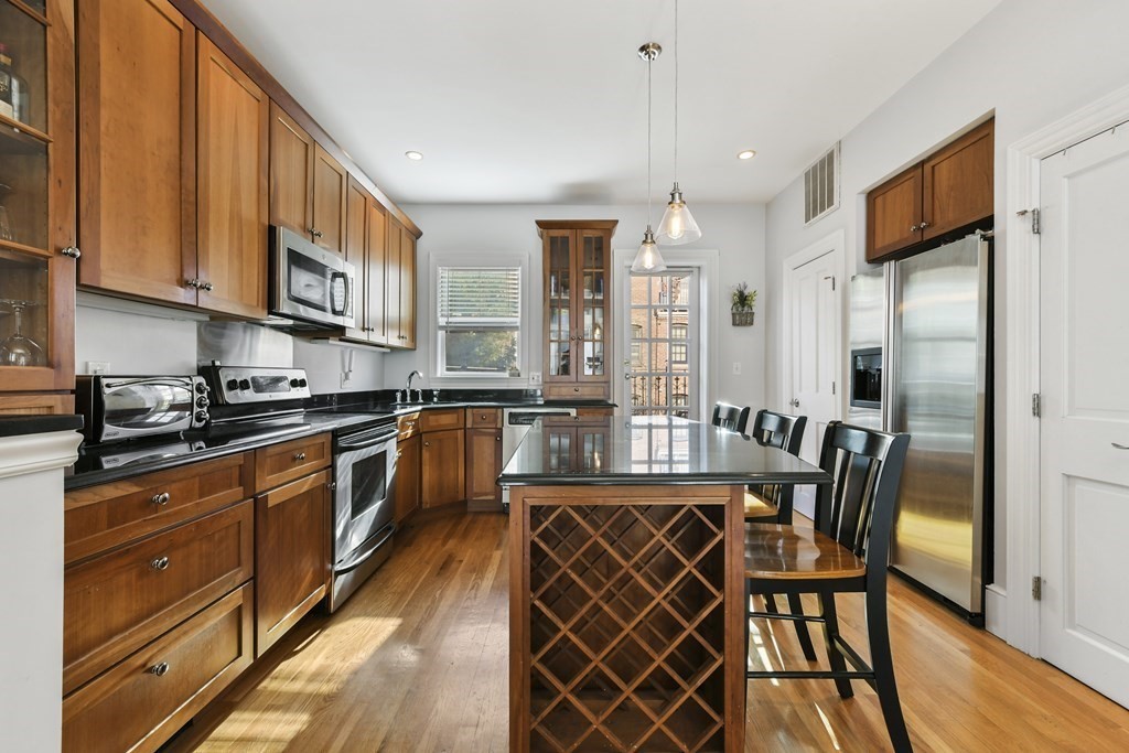 a kitchen with stainless steel appliances granite countertop a stove a sink dishwasher a refrigerator with a dining table and chairs