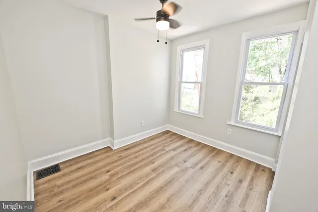 an empty room with wooden floor and windows