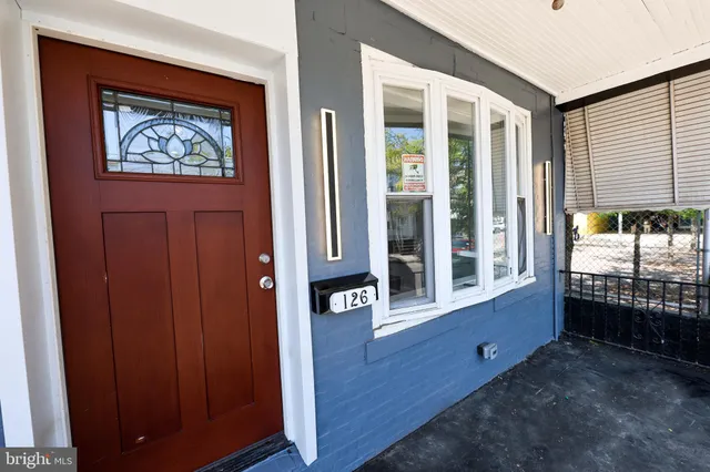 a large white kitchen with kitchen island a stove a sink dishwasher and a fireplace with wooden floor