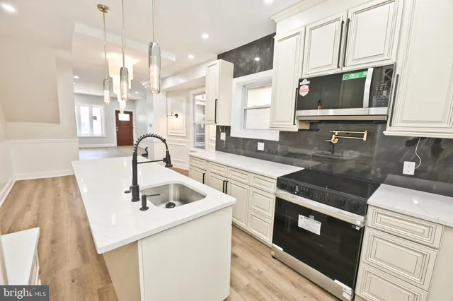 a kitchen with kitchen island a sink a stove a refrigerator and white cabinets