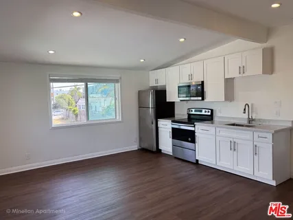 a kitchen with granite countertop white cabinets and wooden floor