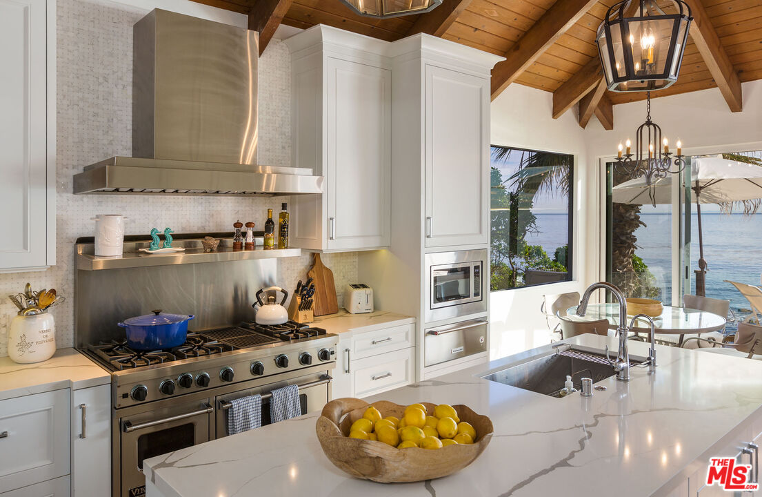 24408 Malibu Road Malibu, CA 90265 - Photo 16 of 44 a kitchen with stainless steel appliances granite countertop a stove and a white cabinets