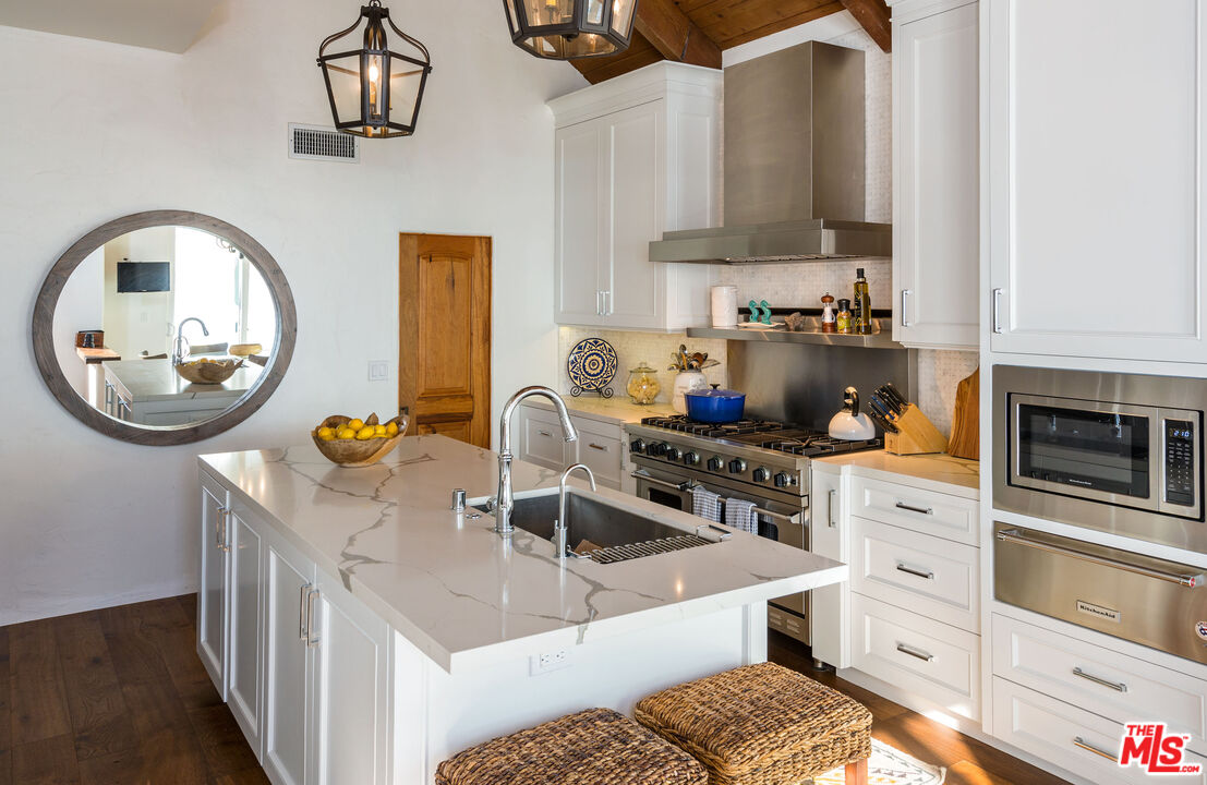 24408 Malibu Road Malibu, CA 90265 - Photo 18 of 44 a kitchen with stainless steel appliances granite countertop a sink a stove and a wooden floors