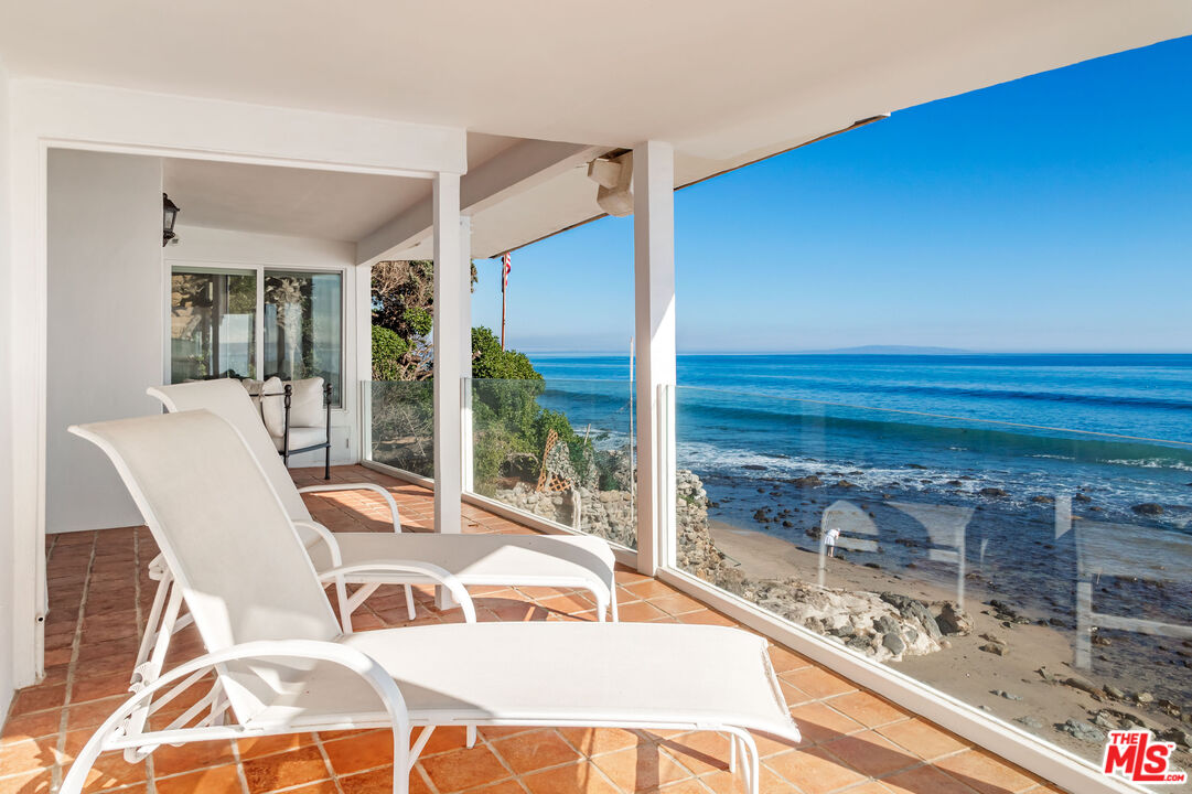 24408 Malibu Road Malibu, CA 90265 - Photo 21 of 39 a view of a patio with table and chairs and couches with wooden floor
