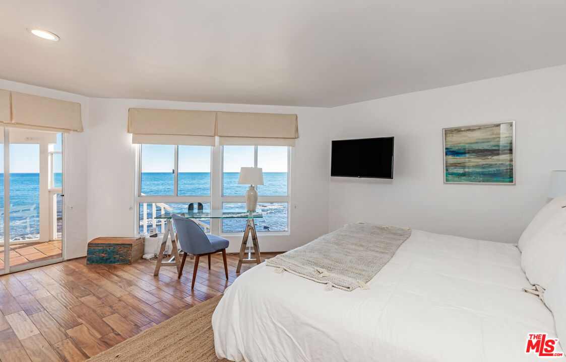 24408 Malibu Road Malibu, CA 90265 - Photo 25 of 39 a bedroom with a bed and wooden floor