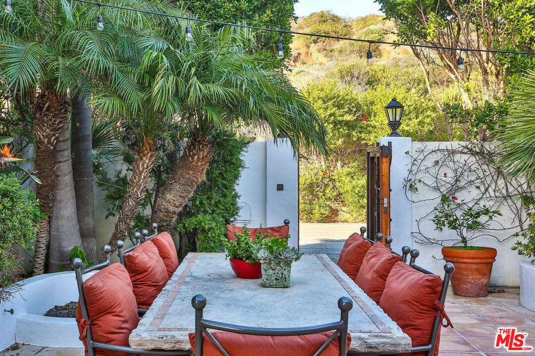 24408 Malibu Road Malibu, CA 90265 - Photo 6 of 44 a view of a patio with couches table and chairs potted plants and a large tree