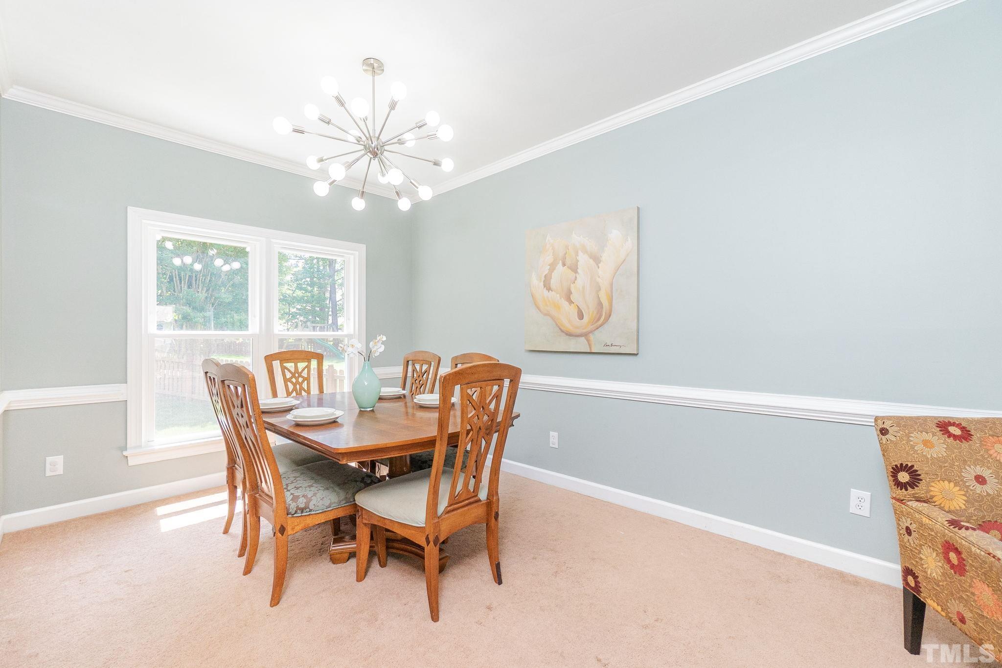 5717 Raddington Street Raleigh, NC 27613 - Photo 11 of 58 a dining room with furniture a chandelier and wooden floor