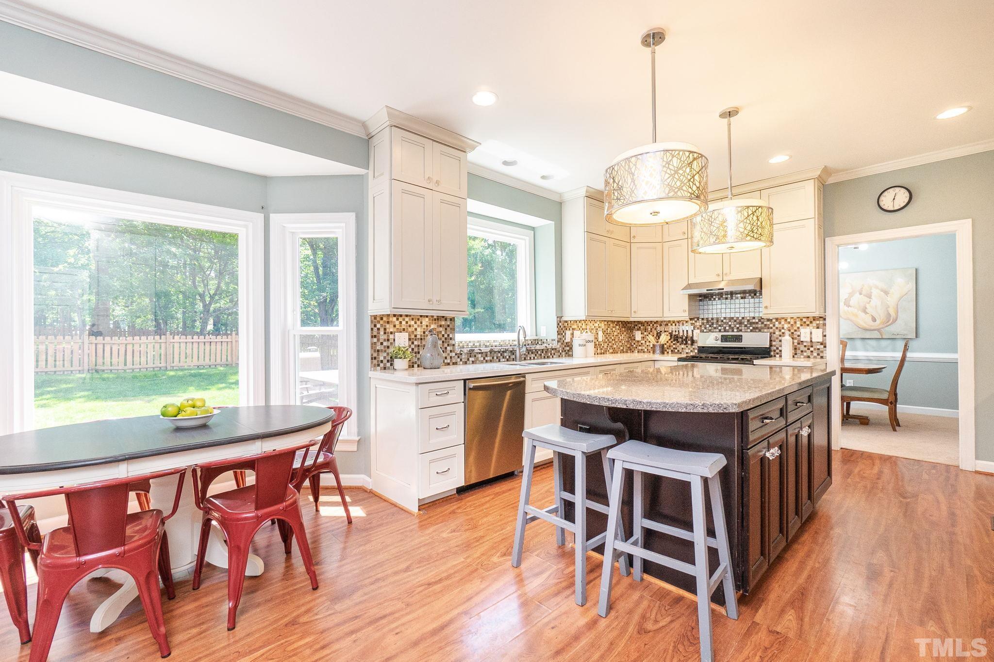 5717 Raddington Street Raleigh, NC 27613 - Photo 16 of 58 a kitchen with a table chairs stove and wooden floor