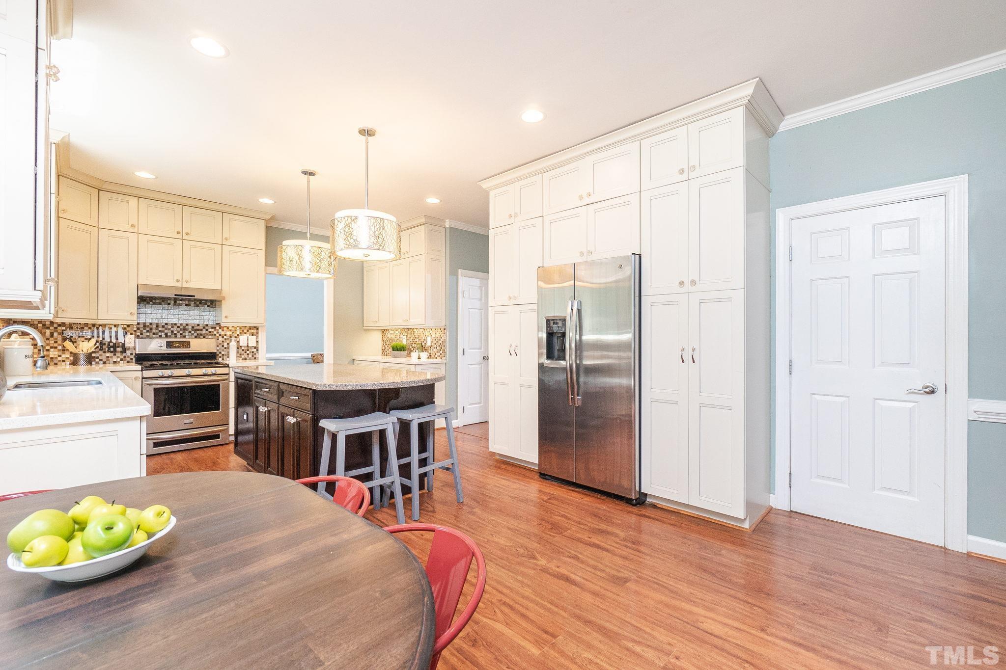 5717 Raddington Street Raleigh, NC 27613 - Photo 18 of 58 a kitchen with stainless steel appliances granite countertop a stove refrigerator and a dining table with wooden floor