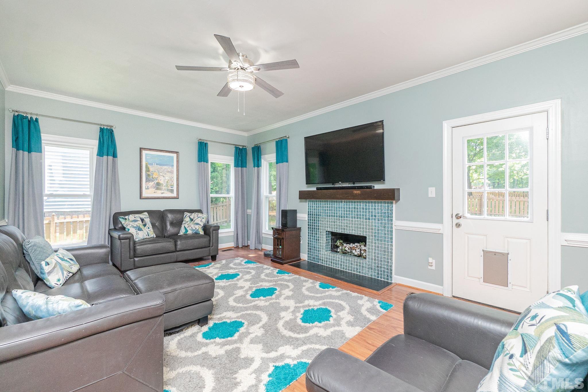 5717 Raddington Street Raleigh, NC 27613 - Photo 25 of 58 a living room with furniture a fireplace and a flat screen tv