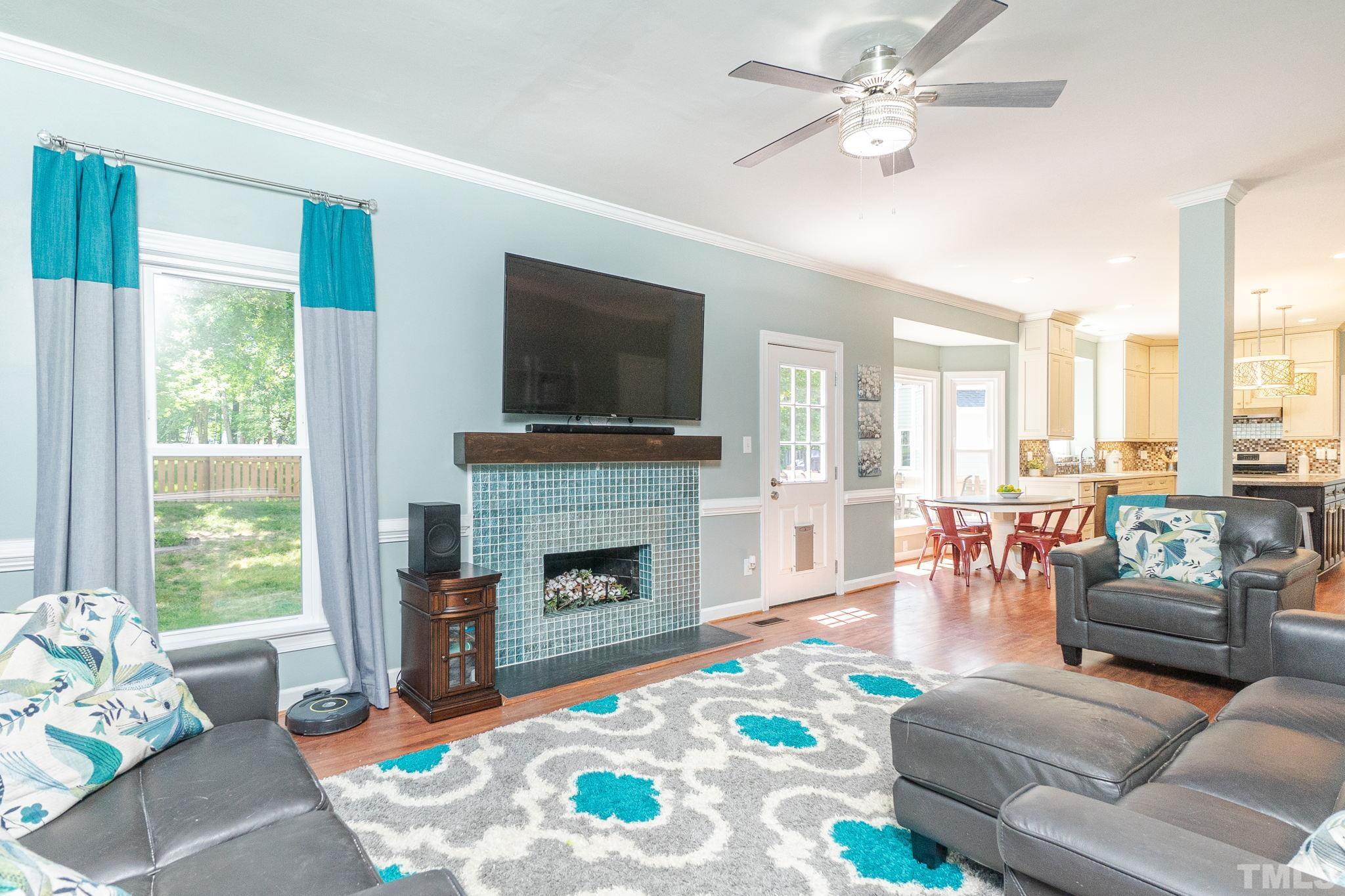 5717 Raddington Street Raleigh, NC 27613 - Photo 27 of 58 a living room with furniture a fireplace and a flat screen tv