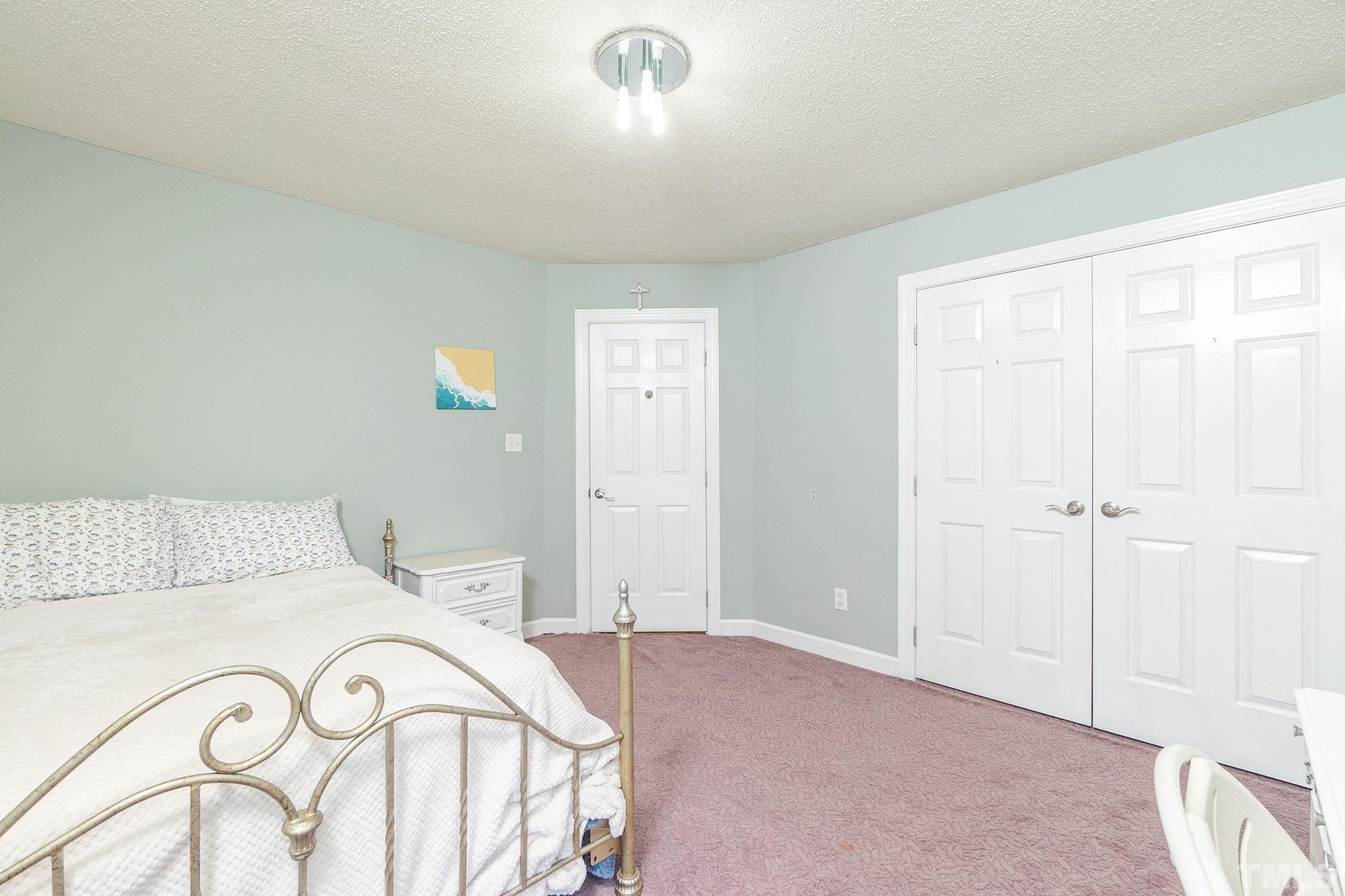 5717 Raddington Street Raleigh, NC 27613 - Photo 35 of 58 a bedroom with a large bed and a chandelier fan