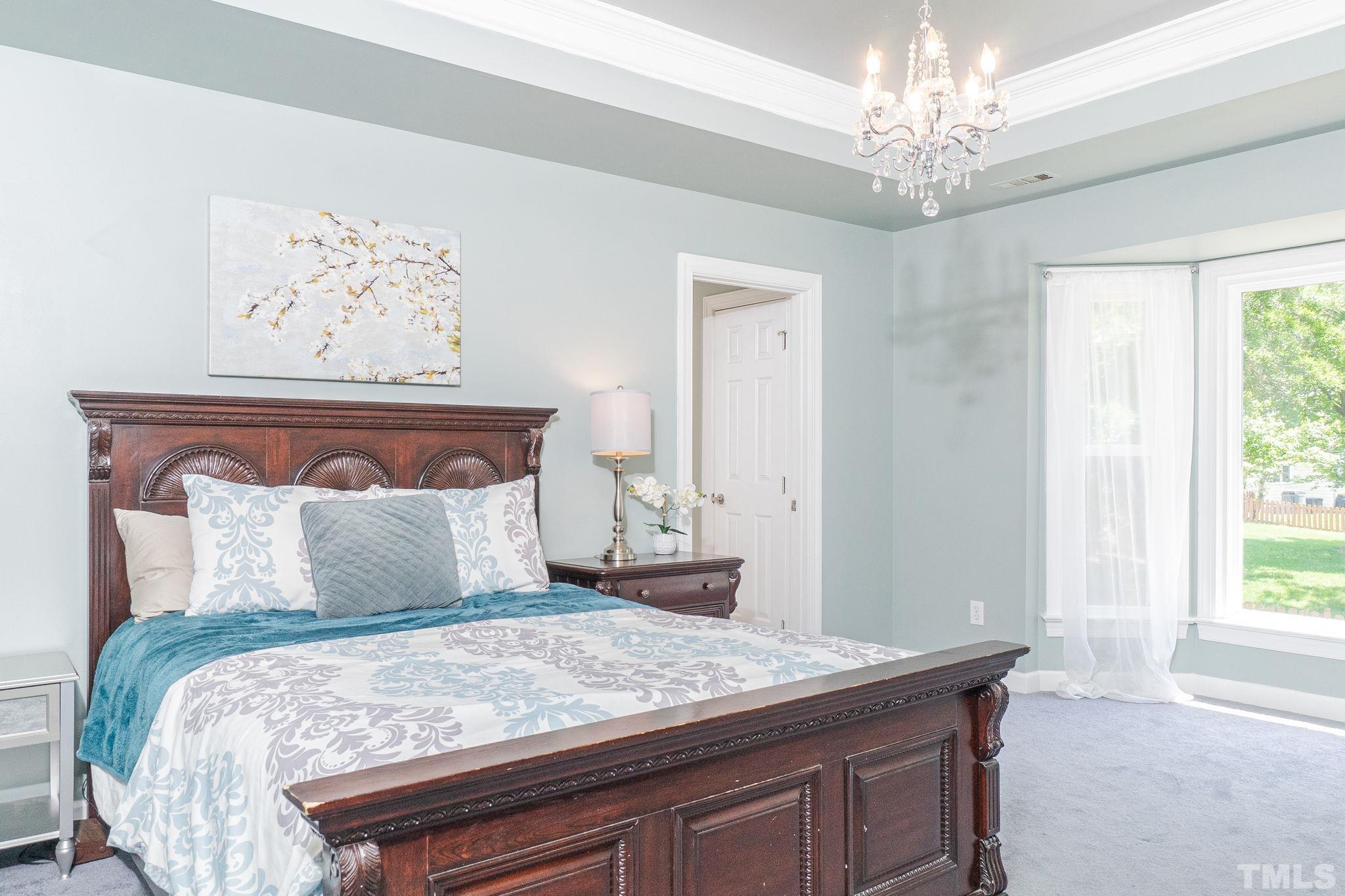 5717 Raddington Street Raleigh, NC 27613 - Photo 39 of 58 a bedroom with a large bed and a chandelier