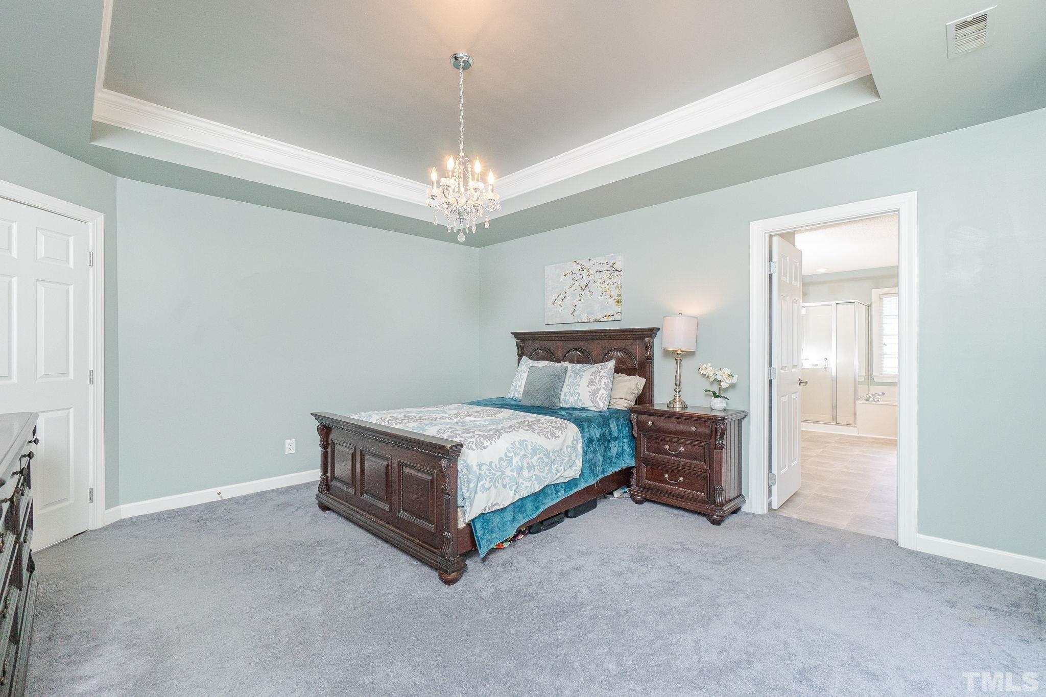 5717 Raddington Street Raleigh, NC 27613 - Photo 40 of 58 a room with a bed and a chandelier