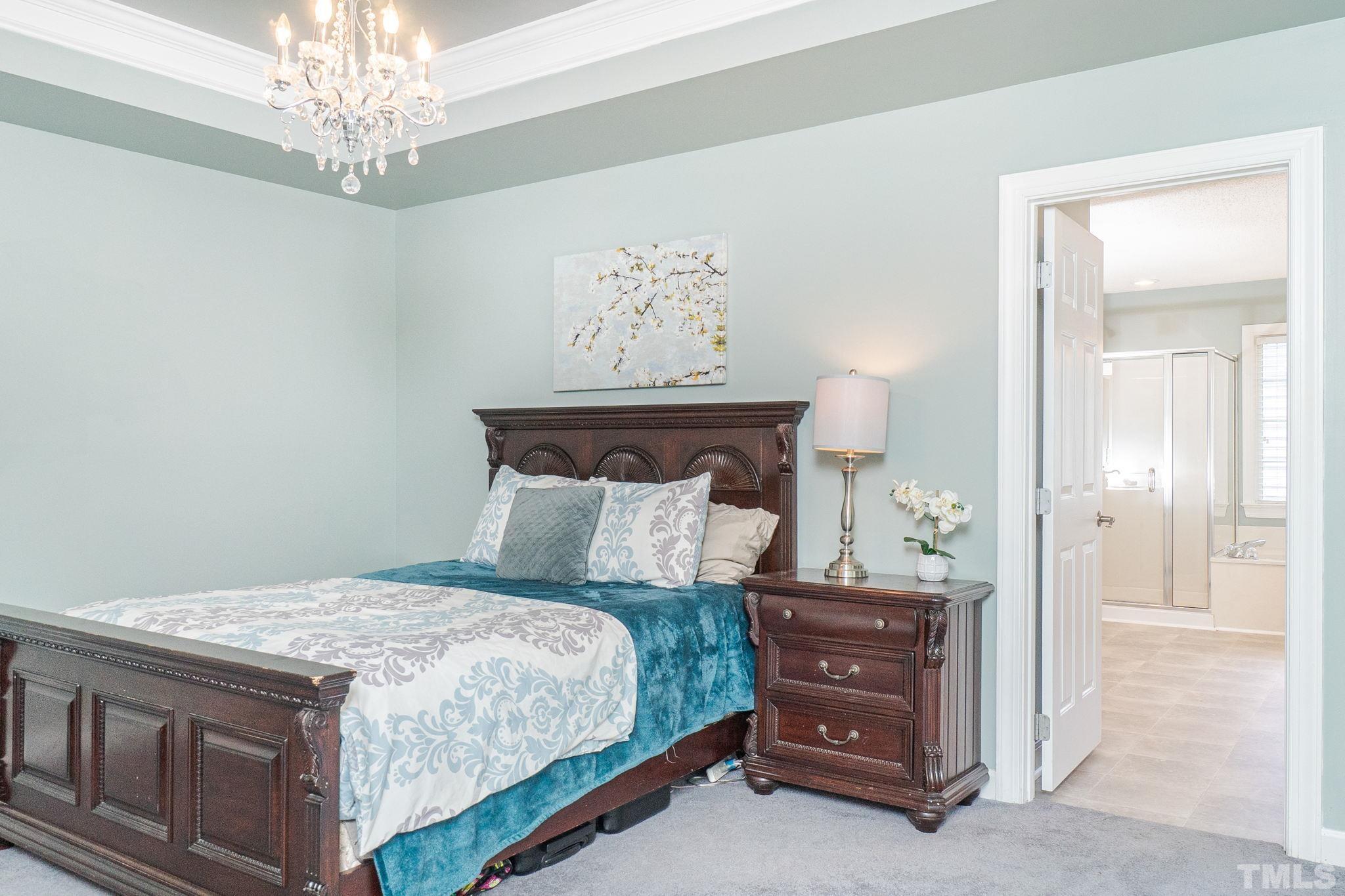 5717 Raddington Street Raleigh, NC 27613 - Photo 41 of 58 a bedroom with a large bed and a chandelier