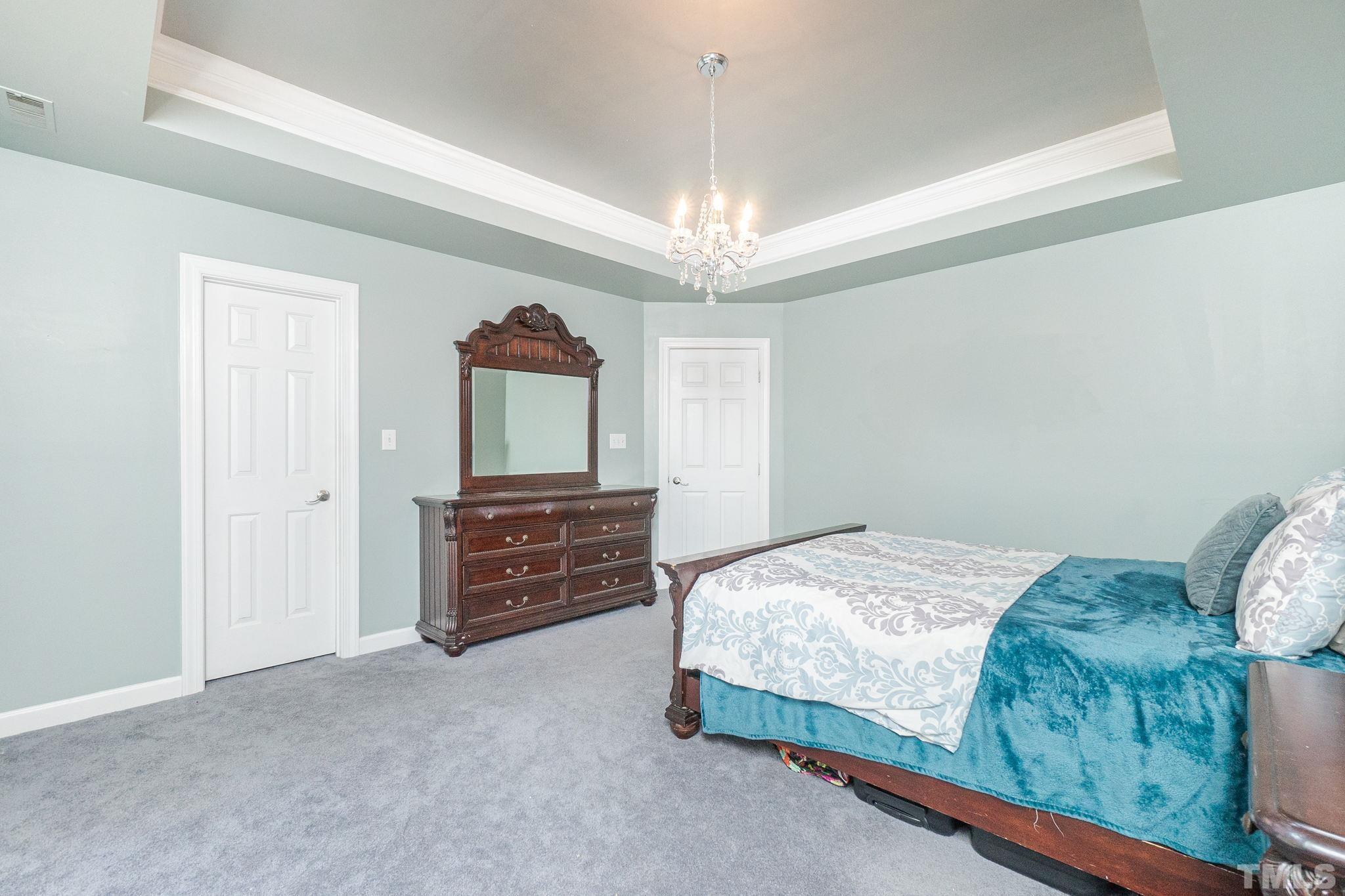 5717 Raddington Street Raleigh, NC 27613 - Photo 42 of 58 a bedroom with a bed and a chandelier