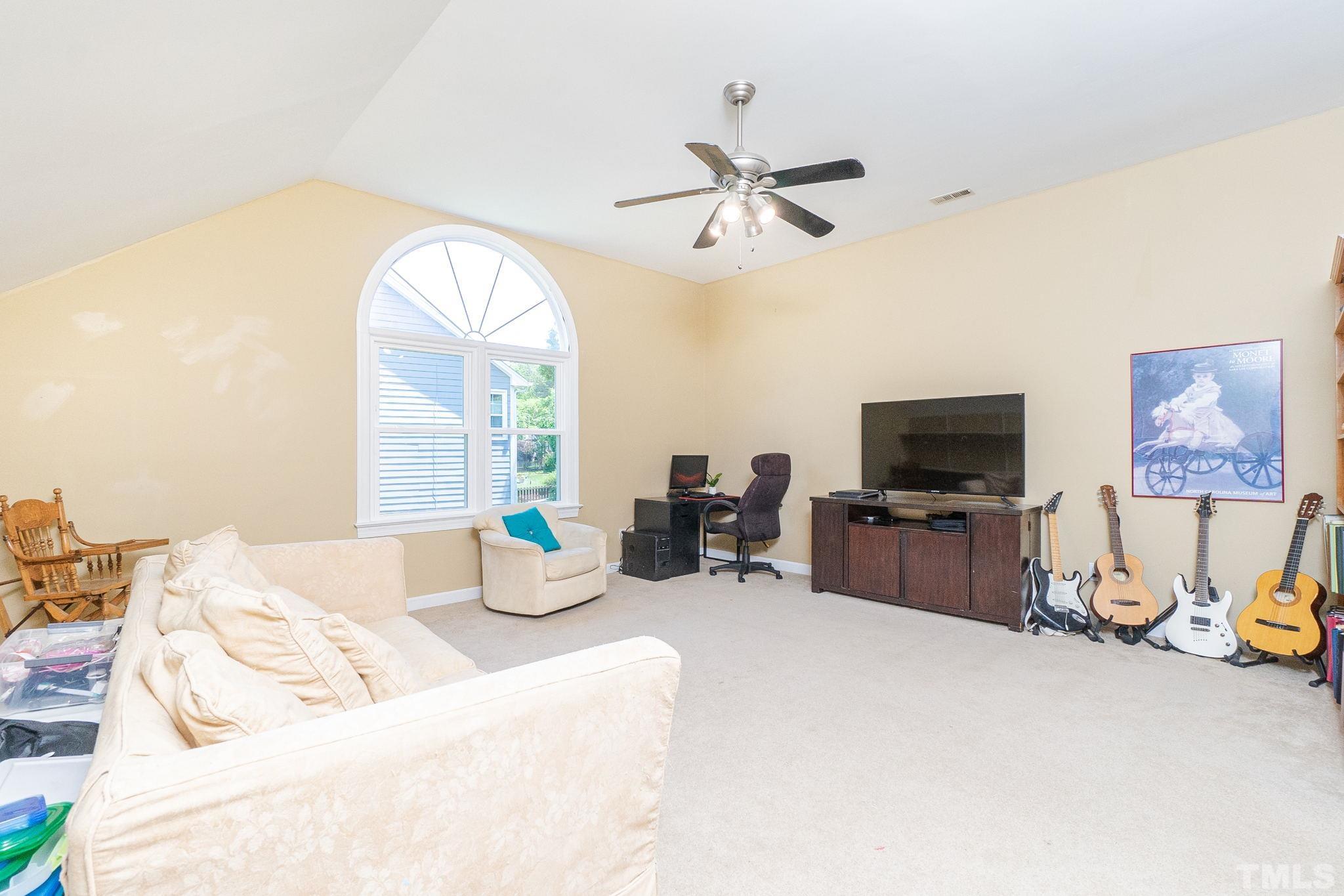 5717 Raddington Street Raleigh, NC 27613 - Photo 46 of 58 a bedroom with bed a flat tv screen and a chandelier