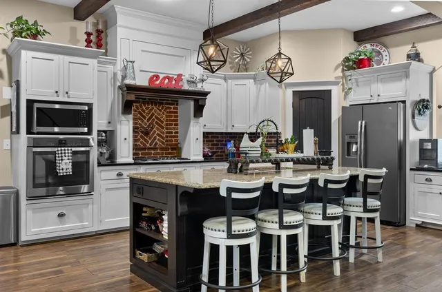 a kitchen with a sink dishwasher a dining table and chairs with wooden floor