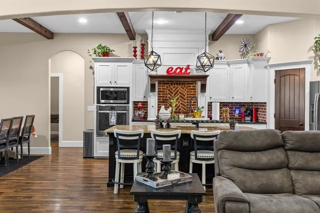 a living room with stainless steel appliances kitchen island granite countertop furniture and a fireplace