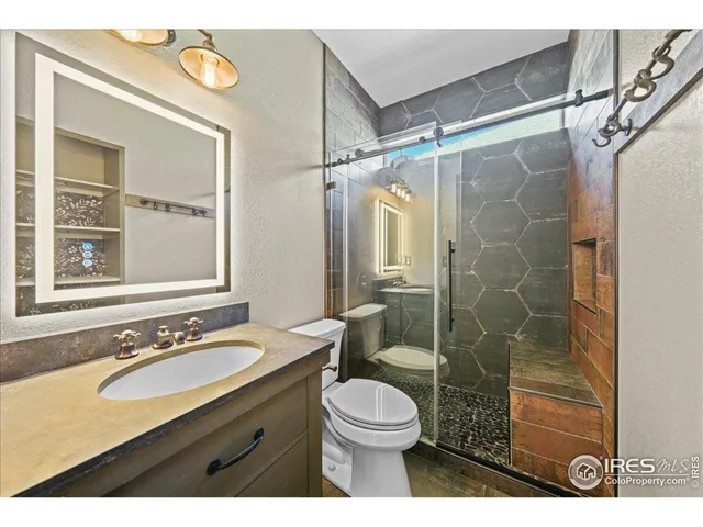a bathroom with a sink vanity granite toilet and shower