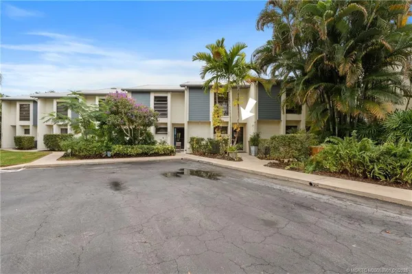 front view of a house with a yard and palm trees