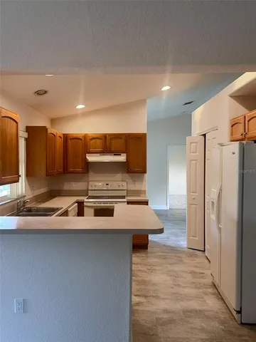 a large kitchen with stainless steel appliances a refrigerator and a stove top oven