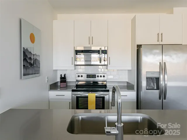 a kitchen with stainless steel appliances granite countertop a stove a refrigerator and a sink with wooden floor