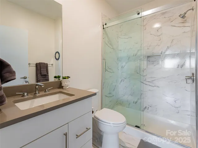 a bathroom with a granite countertop sink a toilet and shower