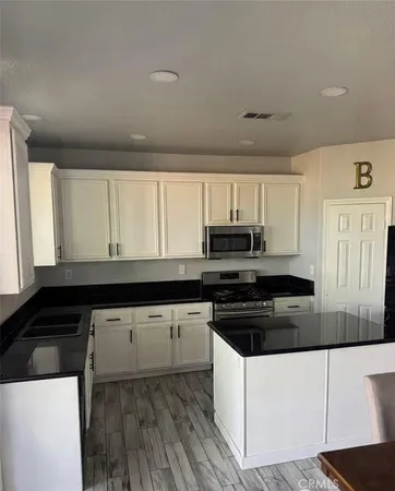 a kitchen with granite countertop a sink a stove and cabinets