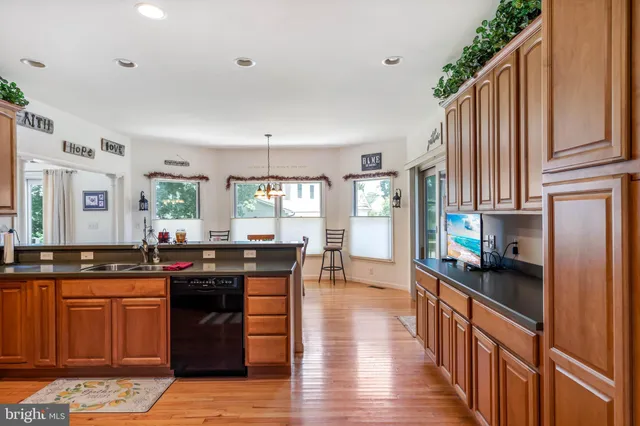 a kitchen with stainless steel appliances granite countertop a stove a sink dishwasher and a refrigerator with wooden floor