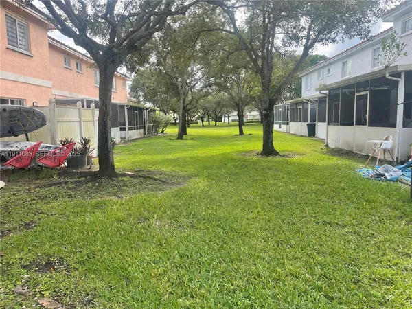 a backyard of a house with plants and large tree