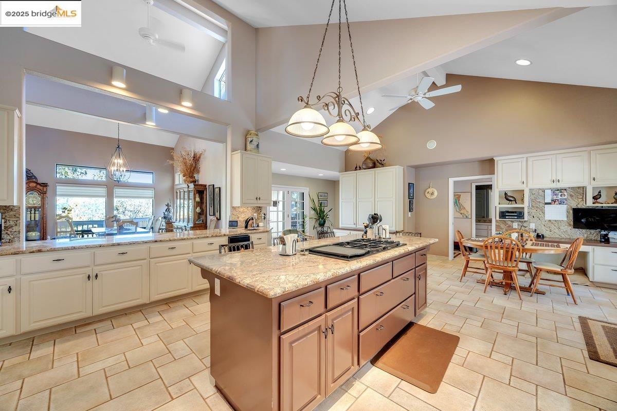 13700 Clements Road Groveland, CA 95321 - Photo 17 of 93 Kitchen featuring backsplash, a ceiling fan, high vaulted ceiling, light stone counters, and hanging light fixtures