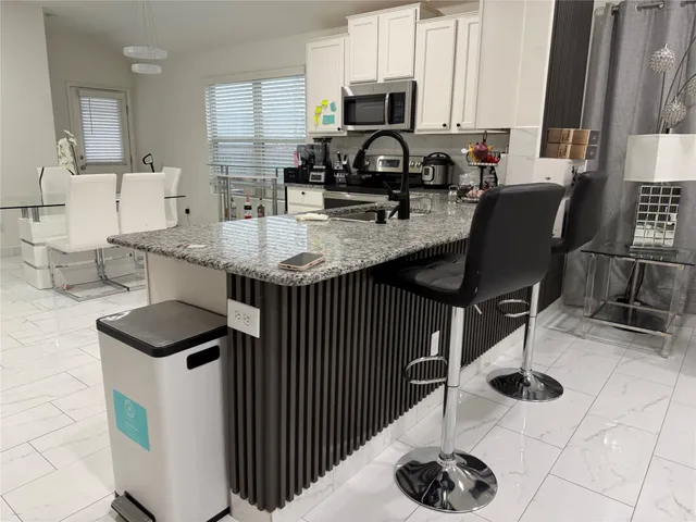 a kitchen with stainless steel appliances kitchen island granite countertop a sink a stove and a microwave