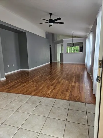 a view of empty room with wooden floor and ceiling fan