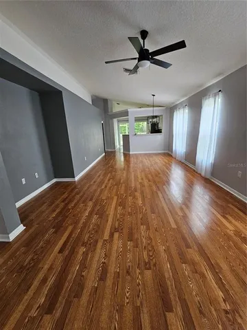 a view of an empty room with window and wooden floor