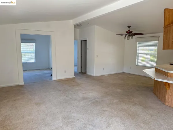 an empty room with windows and fan