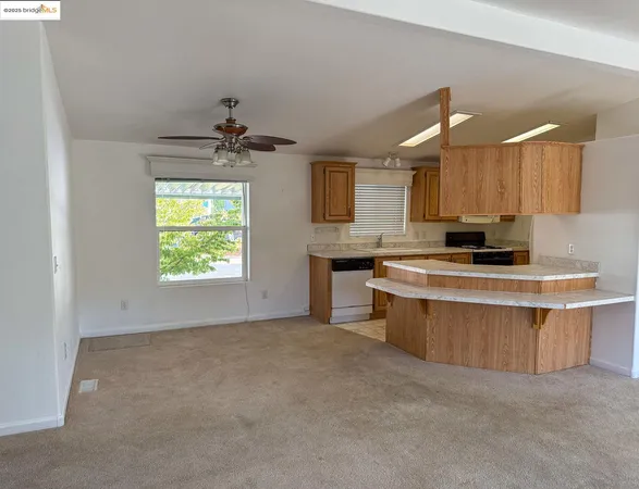 a kitchen with stainless steel appliances a stove a sink a refrigerator a center island and a window