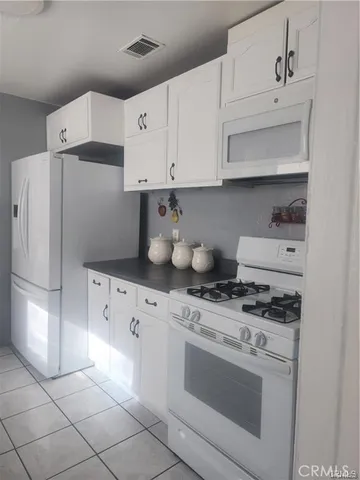 a kitchen with granite countertop white cabinets and white appliances