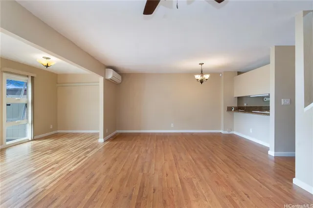a view of kitchen and empty room with wooden floor
