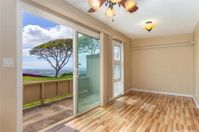 a view of empty room with wooden floor and fan