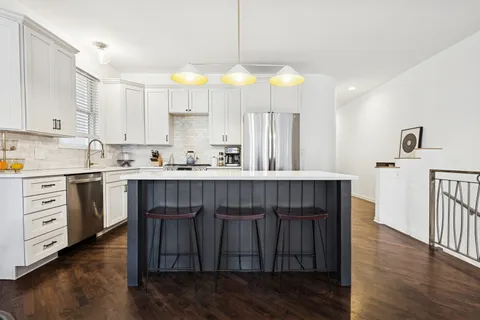 a kitchen with stainless steel appliances granite countertop a sink a stove a refrigerator cabinets and wooden floor