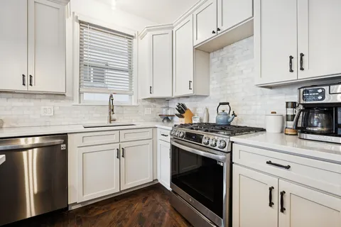 a kitchen with granite countertop white cabinets and stainless steel appliances