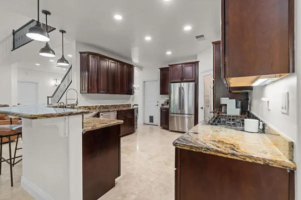 a kitchen with stainless steel appliances granite countertop a refrigerator and a stove top oven