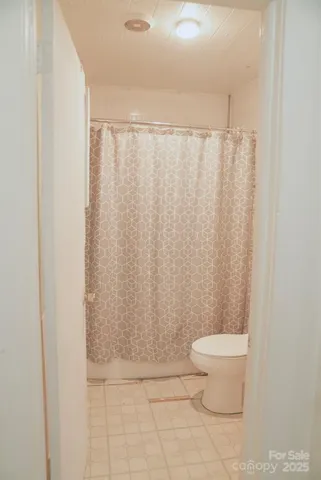a bathroom with a toilet and a shower curtain