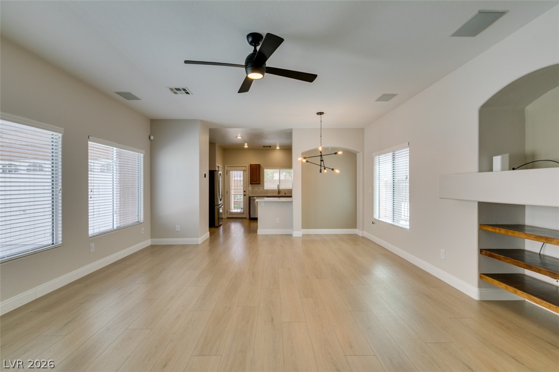 8909 Houston Ridge Avenue Las Vegas, NV 89178 - Photo 2 of 45 Blonde wood-look flooring extends through this airy living space with an arched entry to the kitchen.