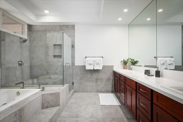 a spacious bathroom with a tub sink shower and mirror