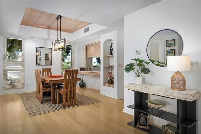 a dining room with wooden floor a chandelier a wooden table and chairs